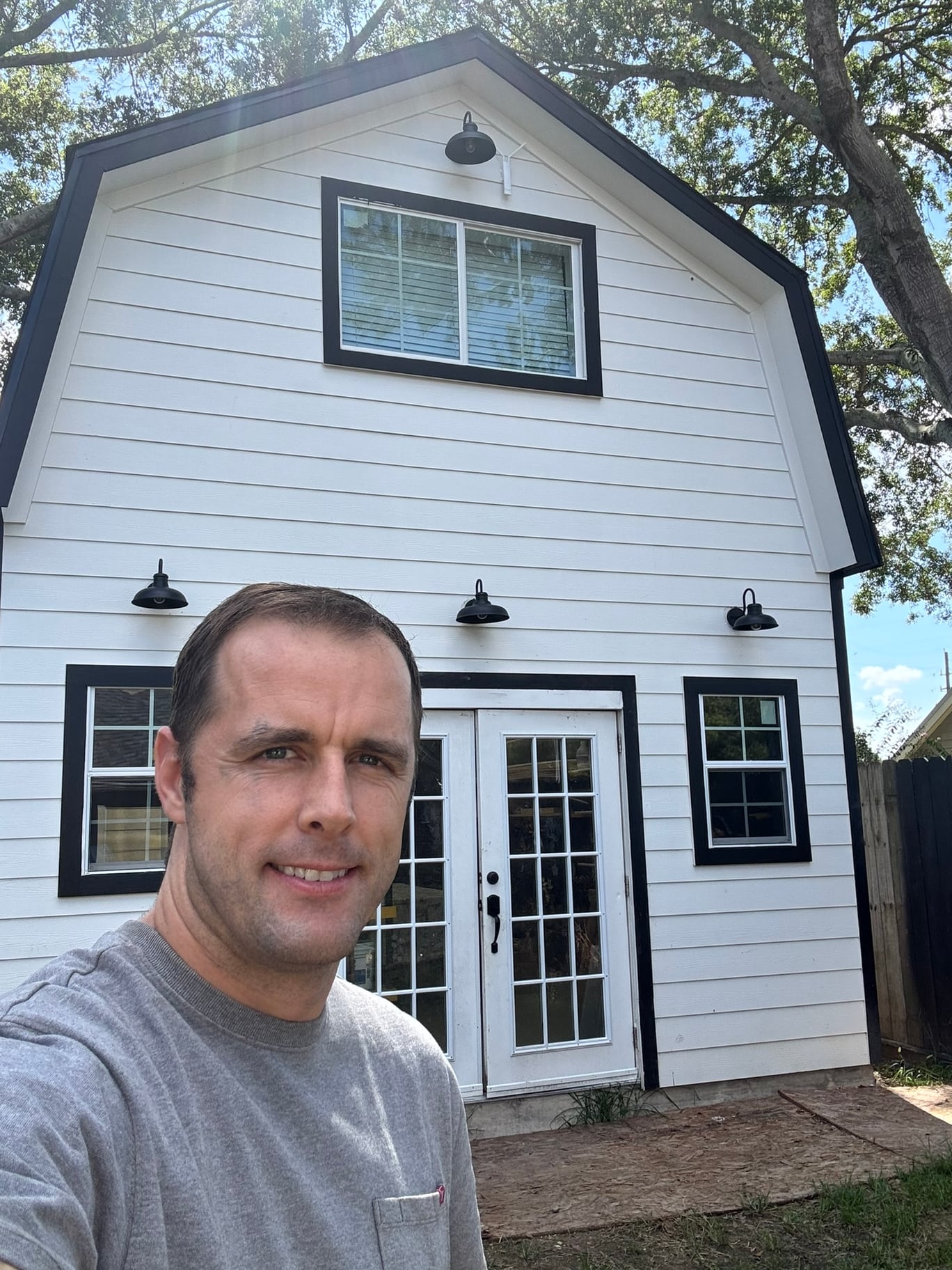 Ben Hilton in front of the white woodworking barn he built.
